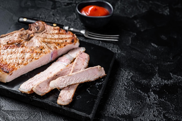 Carne de cerdo en rebanadas a la parrilla o bistec de carne sin huesos Fondo negro Vista superior Espacio de copia