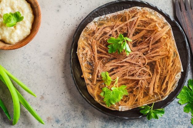 Carne de cerdo y ternera tradicional rusa en gelatina con rábano picante y perejil. Concepto de cocina tradicional rusa.