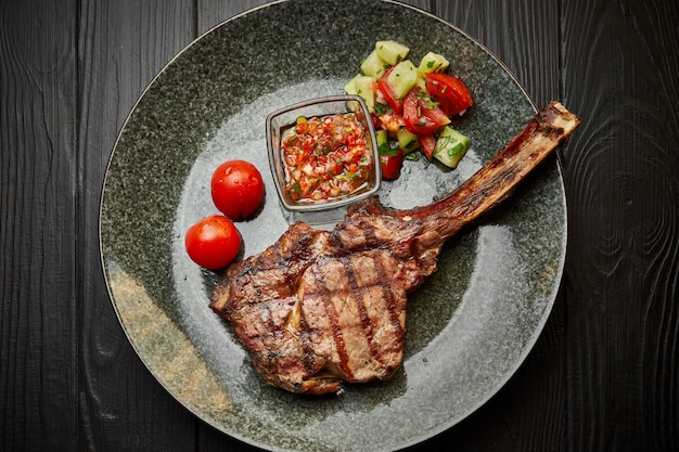 Carne chalagach en un plato con ensalada, tomates y salsa