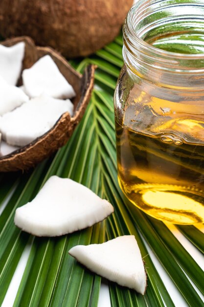Carne de coco y aceite de coco en botella de vidrio en hoja de coco