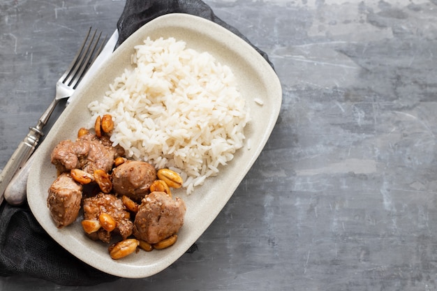 Carne com nozes e arroz cozido no prato branco na mesa de cerâmica