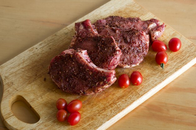 Carne com pimenta vermelha em uma tábua de madeira com tomate