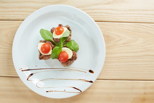 Carne com queijo e tomate num prato branco