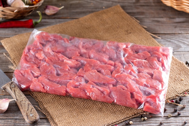 Carne congelada en una bolsa de plástico sobre una mesa de madera. Alimentos congelados.