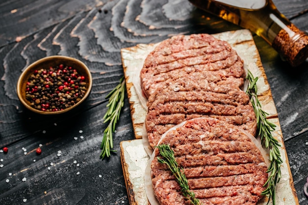 Carne de cordero. Empanadas de hamburguesa de carne cruda con hierbas y especias sobre fondo de madera. banner, menú, lugar de recetas para texto, vista superior