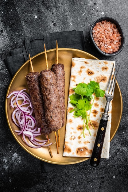 Carne de cordero kofta kebab cebolla y pan plano en plato Fondo negro Vista superior