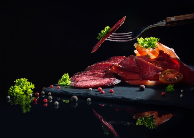 Carne cortada com verduras em um fundo preto