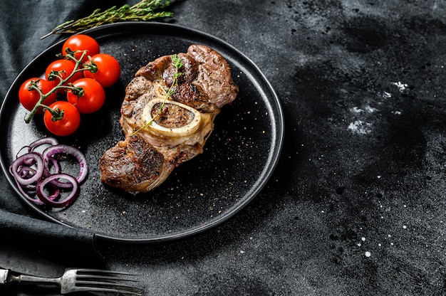 Carne cozida no osso osso buco em molho de tomate. ensopado de carne ossobuco. fundo preto.