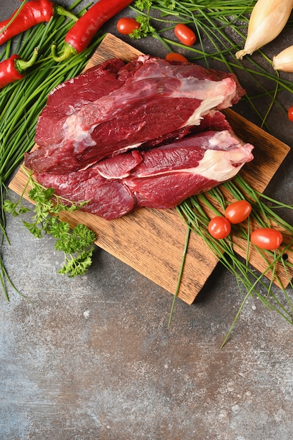 Carne crua com ingredientes para cozinhar na tábua de madeira marrom.