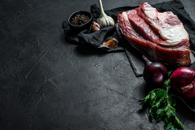 Carne crua com osso na parede preta. Vista do topo. Espaço para texto