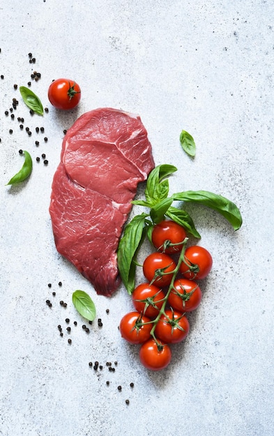 Foto carne crua com tomate e manjericão em um fundo de pedra com espaço para texto