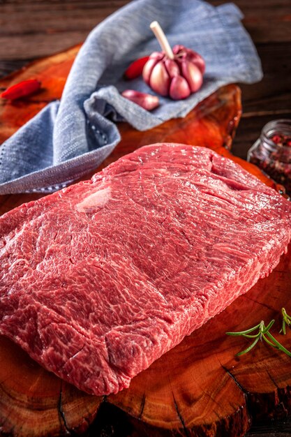 Carne crua de denver de mármore em uma tábua de madeira resinada com especiarias e alecrim