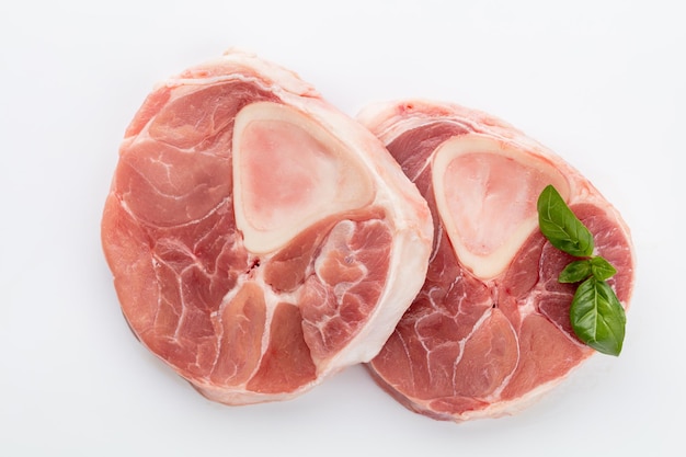 Carne crua e carne de porco em fundo branco.