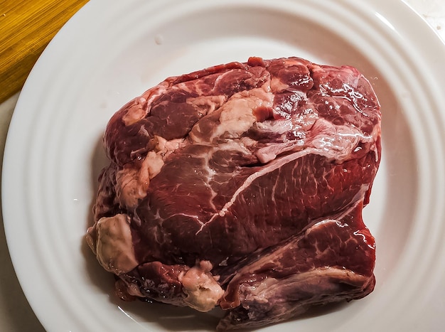 Carne crua em cima de bife em um prato branco conceito de comida caseira