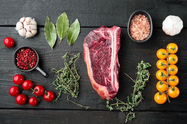 Carne crua fresca em mármore, bife de clube de angus preto e ingredientes na mesa de madeira preta