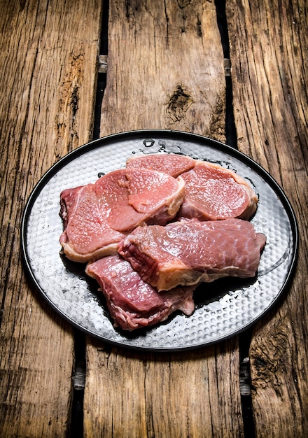 Carne crua fresca em um carrinho. Em fundo de madeira.