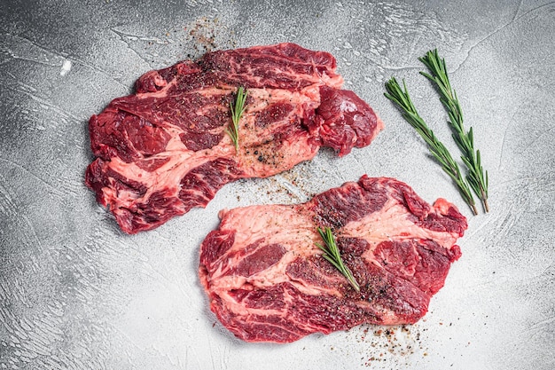 Carne crua marmoreada Bifes cozinhando com temperos e azeite bifes de costela de vaca fresca Fundo branco Vista superior