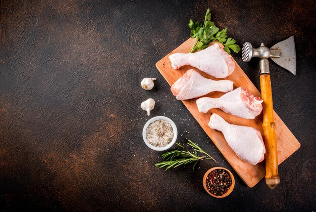 Carne crua, pernas de frango, com ervas e especiarias n fundo enferrujado escuro, cópia espaço vista superior