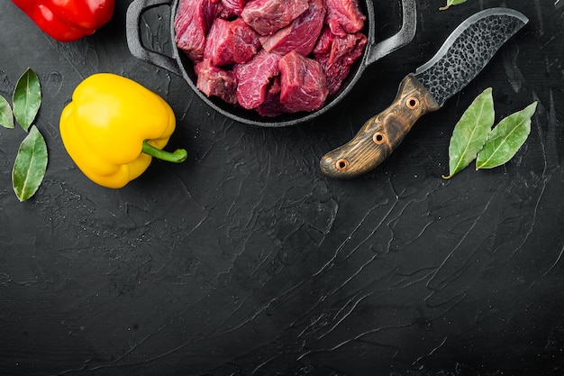 Carne cruda cortada en cubitos para guiso con pimiento dulce en sartén de hierro fundido