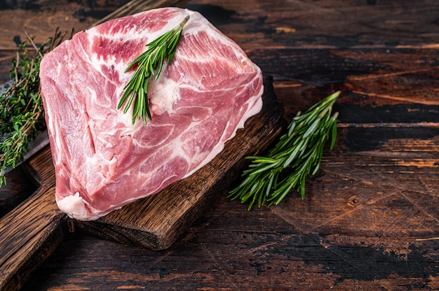 Carne cruda de cuello de cerdo para chuletas frescas sobre tabla de cortar de madera con cuchilla de carnicero