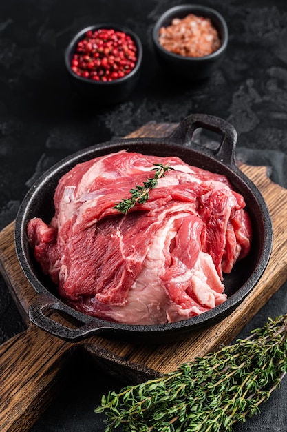 Carne cruda de cuello de cordero deshuesado en una sartén con hierbas Fondo negro Vista superior