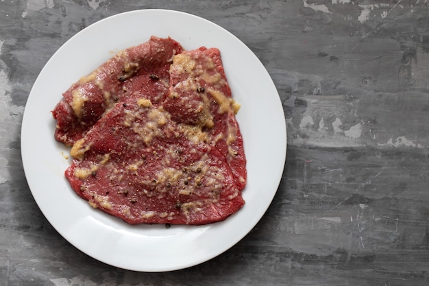 Carne cruda con especias en plato blanco