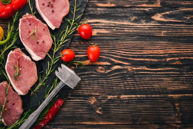 Carne cruda Filete de ternera con romero y especias sobre un fondo de madera negra Vista superior Espacio libre para texto