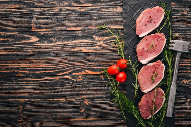 Carne cruda Filete de ternera con romero y especias sobre un fondo de madera negra Vista superior Espacio libre para texto