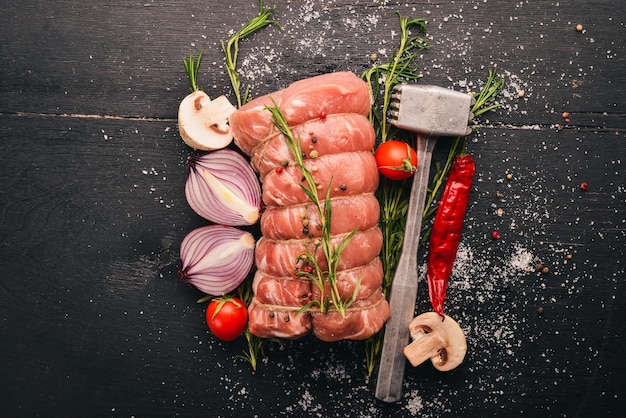 Carne cruda Filete de ternera con verduras frescas y romero y especias sobre un fondo de madera negra Vista superior Espacio libre para texto