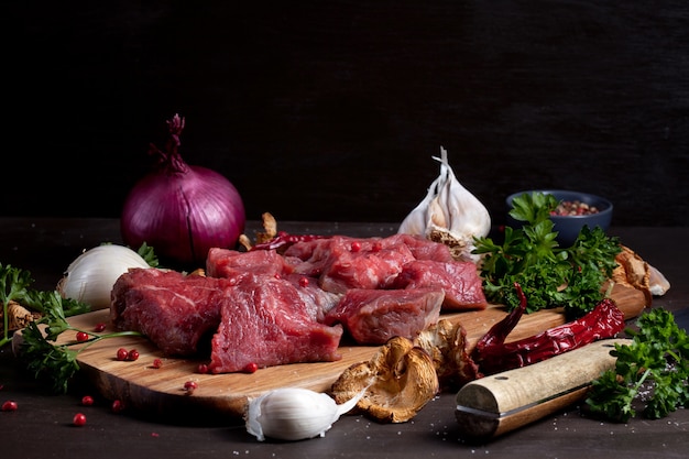 Carne cruda fresca; Botella de vino y verduras orgánicas de otoño estacionales sobre tabla de madera lista para cocinar