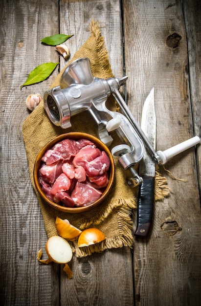 Carne cruda fresca en una cebolla con picadora, cuchillo y especias sobre tela vieja