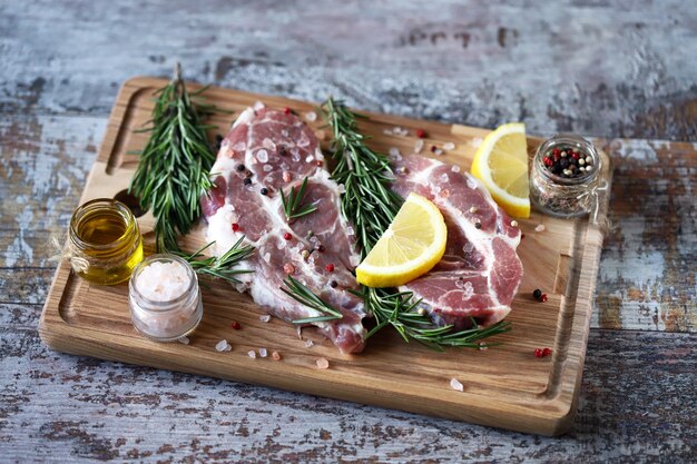 Carne cruda fresca con romero y especias sobre una tabla de madera