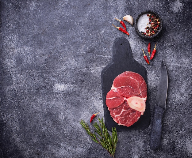 Carne cruda osso buco sobre tabla para cortar pizarra