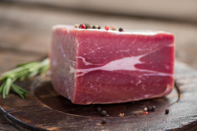 Carne cruda y pimienta entera. Pedazo de carne en placa de madera. Lomo para bife. Es la hora de la barbacoa.