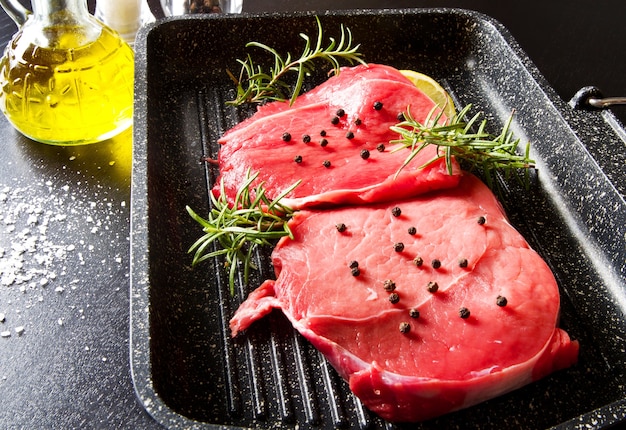 Carne cruda en rodajas en la olla de placa sobre fondo negro