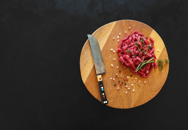 Carne cruda en rodajas sobre una tabla de madera. Preparación de ternera Stroganoff.