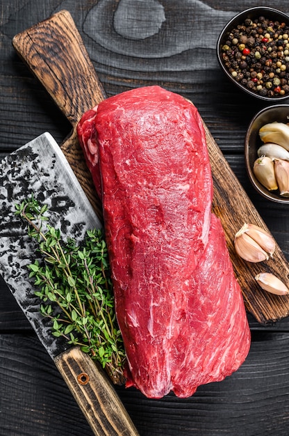 Carne cruda de solomillo de ternera para filetes filete mignon sobre una tabla de cortar de madera con cuchilla de carnicero