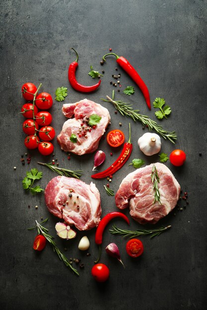 Carne cruda, tomates y especias en gris