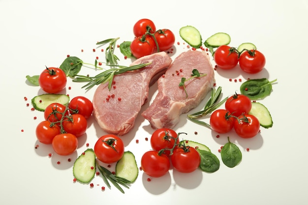 Carne cruda tomates pepinos y especias sobre fondo blanco.