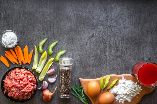 carne cruda con verduras y especias sobre fondo de madera