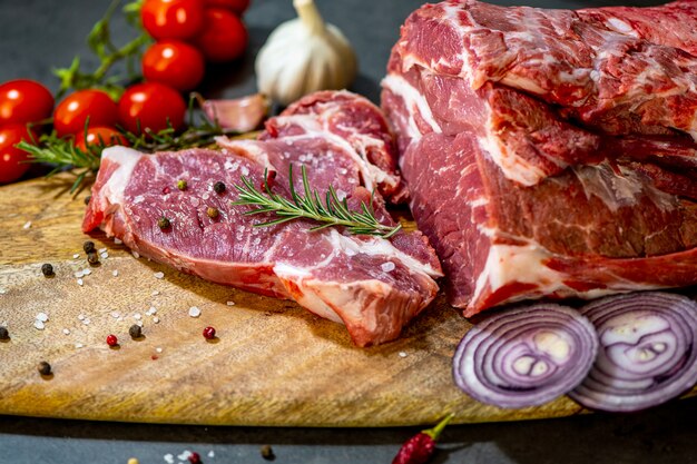 carne cruda y verduras en la tabla de cortar sobre fondo de cemento oscuro