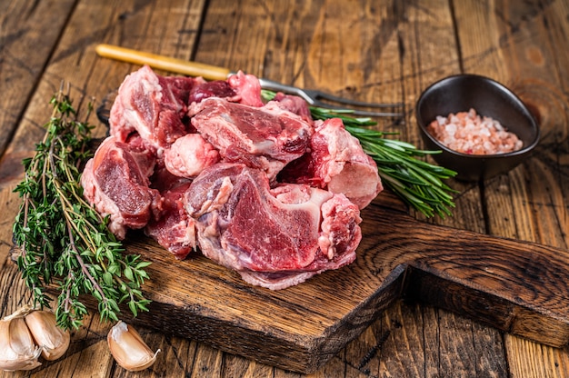 Carne de boi crua cortada em cubos para guisado com osso. de madeira