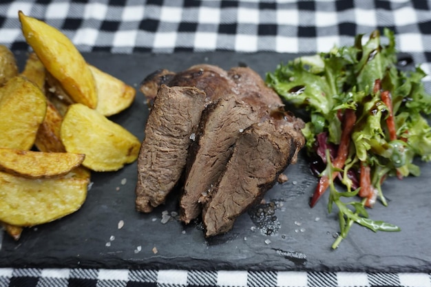 Carne de canguru com batatas fritas e salada no prato