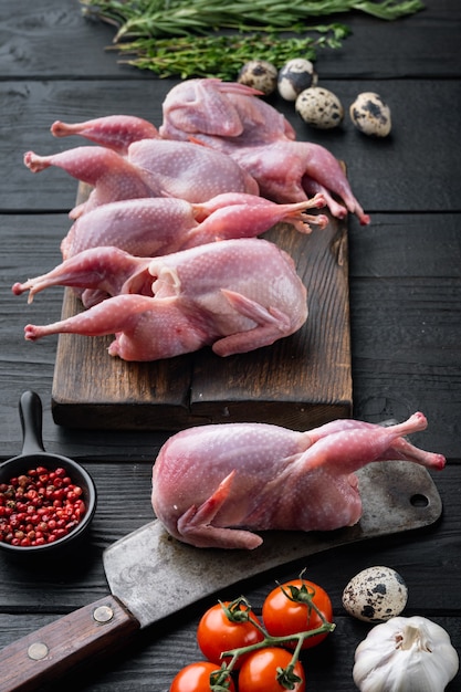 Carne de codorna inteira com especiarias, ervas, vegetais, na mesa de madeira preta