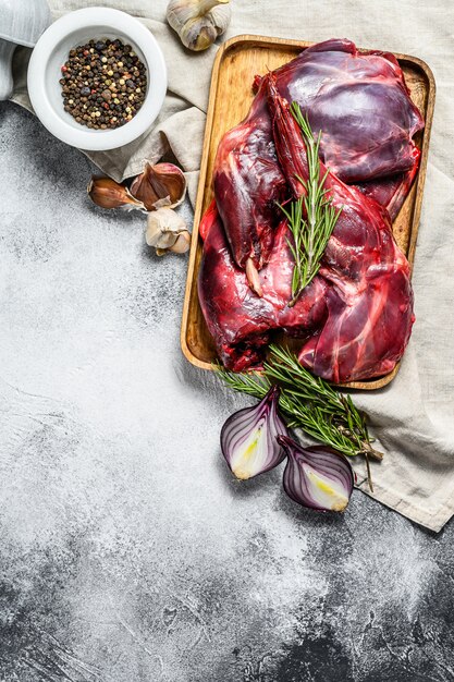 Carne de coelho. coelho fresco cru fazenda em uma mesa de madeira com legumes e especiarias. vista do topo. copie o espaço