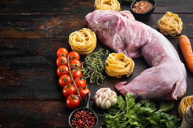 Carne de coelho crua e ingredientes de cozinha ensopado de tagliatelle definido, no fundo da velha mesa de madeira escura, com espaço de cópia para o texto