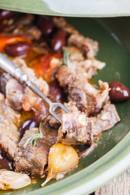 Carne de cordeiro cozida em um tagine com azeitonas, alho