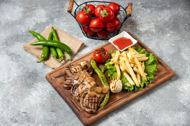 Carne de cordeiro grelhada com batatas fritas na placa de madeira