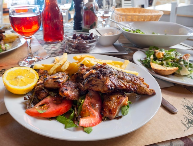 Carne de cordeiro grelhada com salada de batatas fritas e vinho grego da casa na mesa em uma taverna na Grécia
