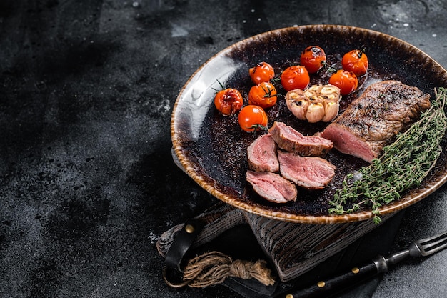 Carne de filé de cordeiro no prato com tomate grelhado carne de carneiro grelhado bife de lombo Fundo preto Vista superior Espaço para texto